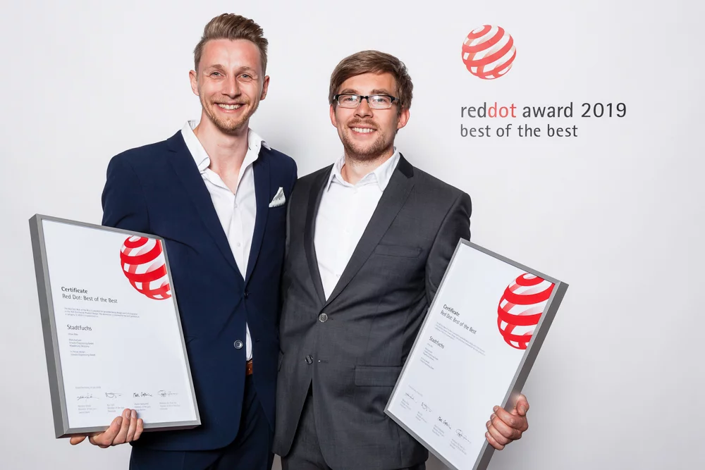 Gründer Sebastian und Ramon stehen nebeneinander, jeder hält eine Red Dot Award Urkunde in der Hand 