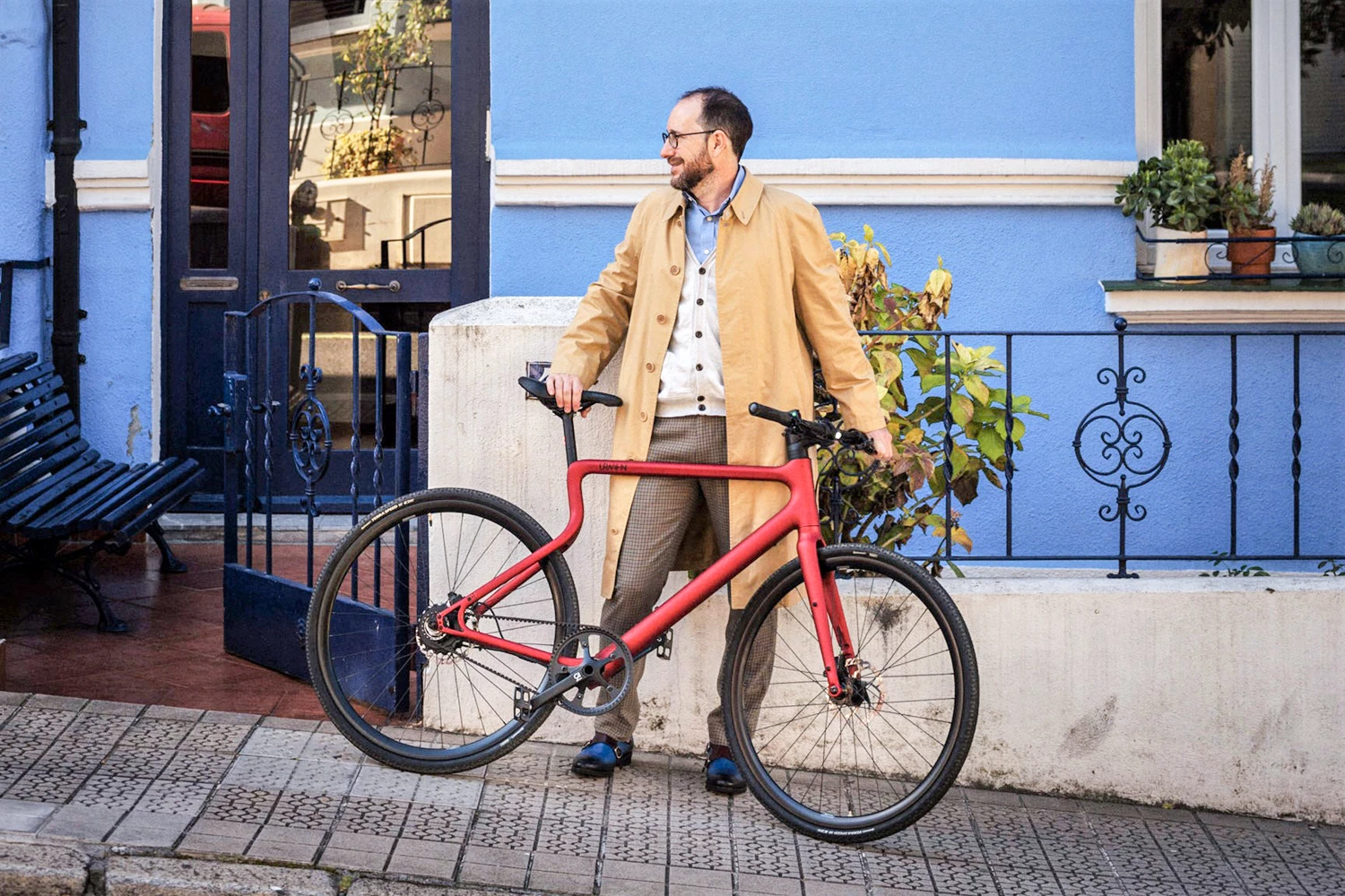 Urban E-Bike Statduchs in Oxidrot wird von einem elegant gekleideten Mann an der Seite einer Straße gehalten
