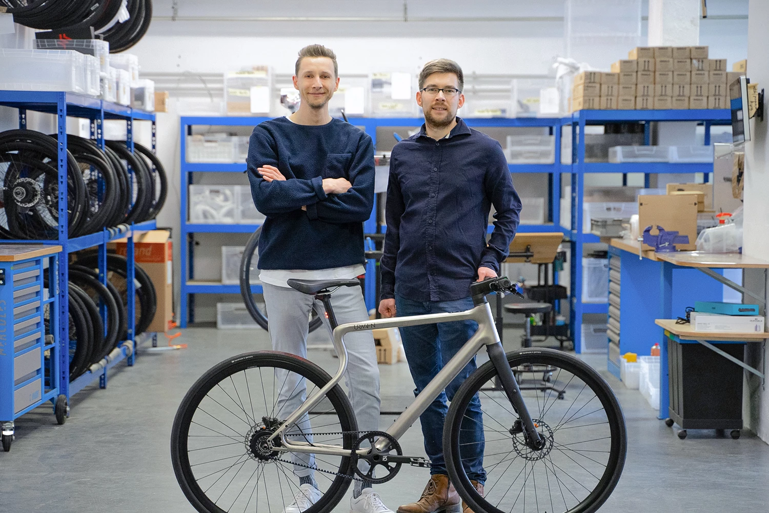 URWAHN Gründer Sebastian und Ramon stehen mit Stadtfuchs Urban E-Bike stehend in der Manufaktur