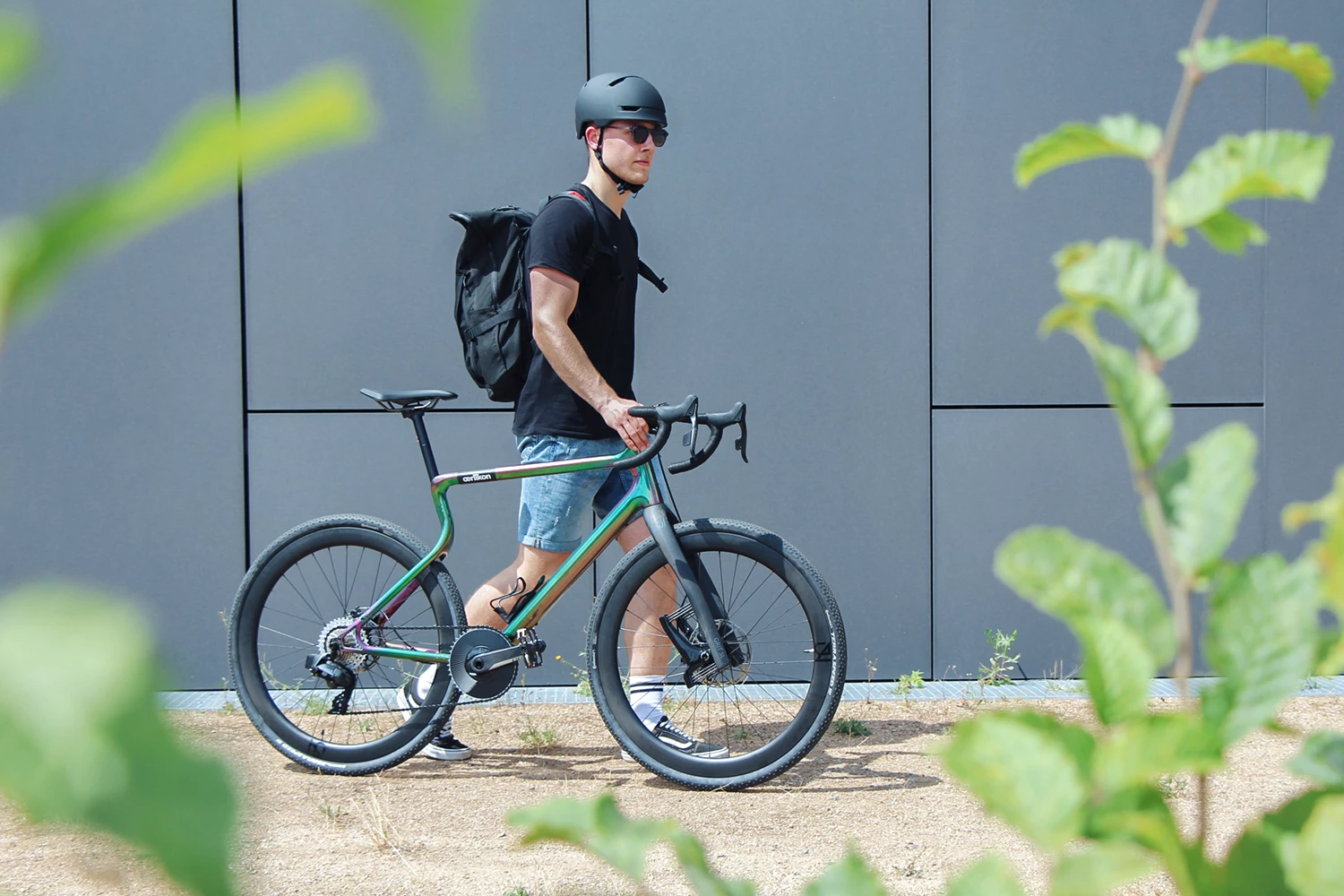 Gravel E-Bike Waldwiesel Oelrikon Edition wird von Fahrer am Vorbau vor einem grauen Hintergrund geführt